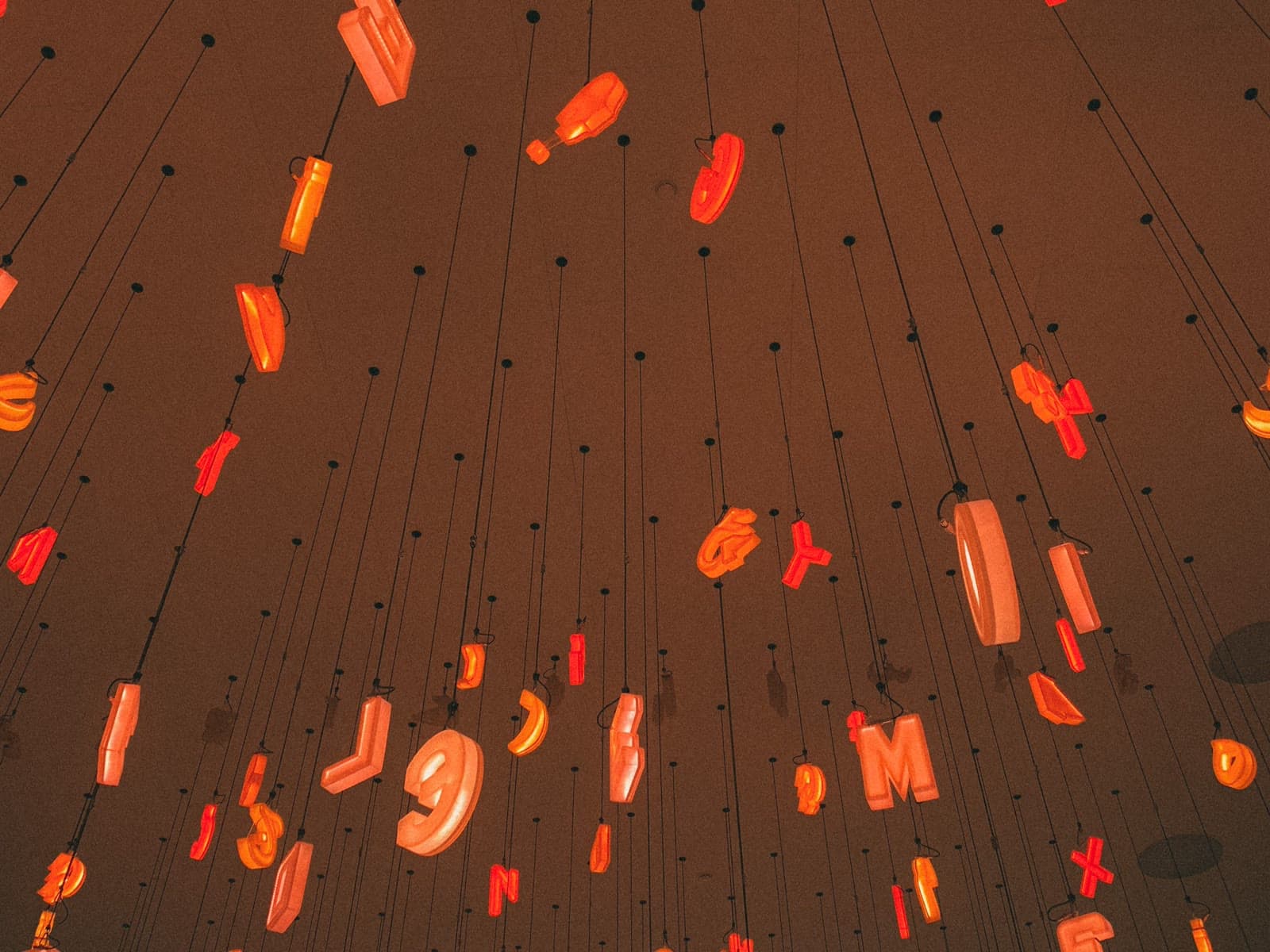 Glowing orange letters hanging from a dark ceiling