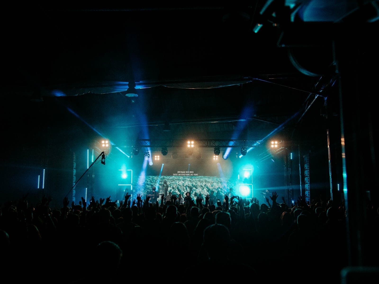 A concert at night, the stage lit in teal, a full room